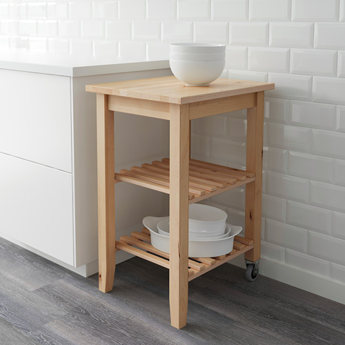 Carro de cocina de madera con ruedas, sosteniendo cuencos blancos, contra la pared de azulejos blancos.