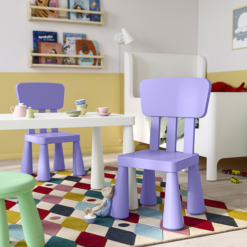 Área de juegos para niños con sillas MAMMUT moradas, mesa blanca, alfombra colorida y configuración de juguetes; Las sillas moradas son pequeñas y ligeras.