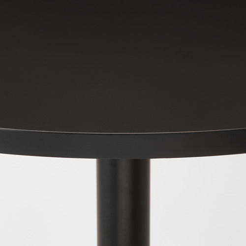 Primer plano de un elegante y moderno tablero redondo negro con acabado liso y brillante y robusta pata de metal.