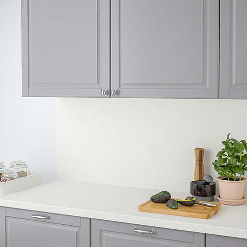 Encimera de cocina moderna con armarios grises y encimera redondeada de SÄLJAN, con aguacates, tabla de cortar y accesorios.