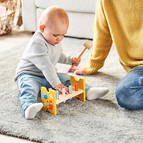 Bebé jugando con el juguete de martilleo UPPSTÅ, golpeando tapones, guía de adultos cerca.