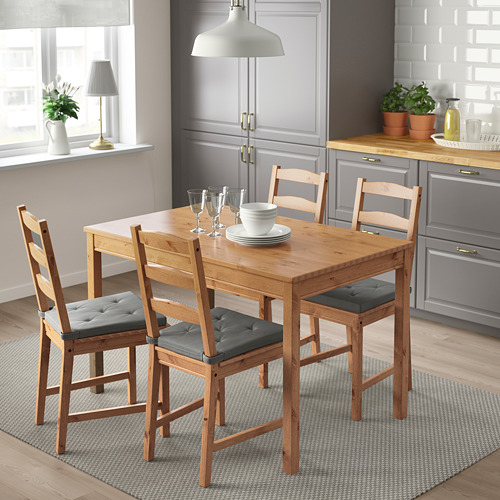 Juego de comedor JUSTINA con 4 sillas de madera, cojines grises, sobre alfombra en la cocina.