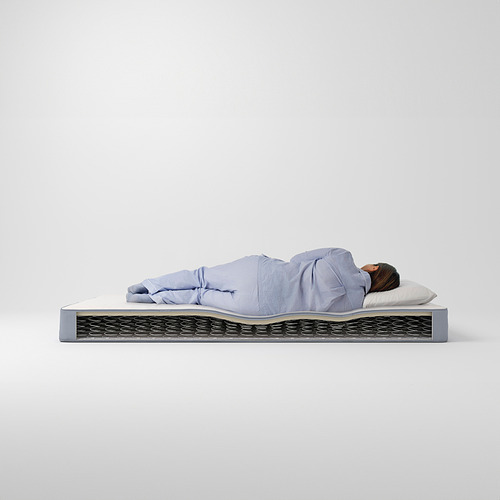 Una persona duerme en un colchón VESTMARKA azul claro, con bobinas visibles y un diseño sencillo.