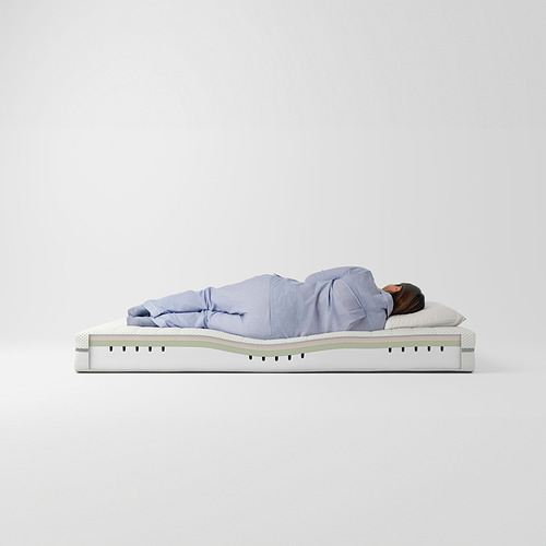 Una persona durmiendo en un colchón de espuma ÅKREHAMN azul claro, diseñado con tres capas de confort.