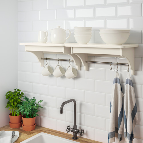 El estante blanco contiene tazas, tazones y ollas; Ganchos debajo para colgar toallas, cocina contra la pared de azulejos.