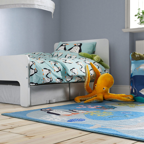 BLÅVINGAD Juguete de pulpo naranja claro sobre alfombra azul junto a la cama, suave y reciclado.