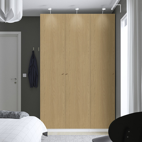 Dormitorio moderno con gran armario PAX de madera clara, pared gris, chaqueta colgante y cama parcialmente visible.