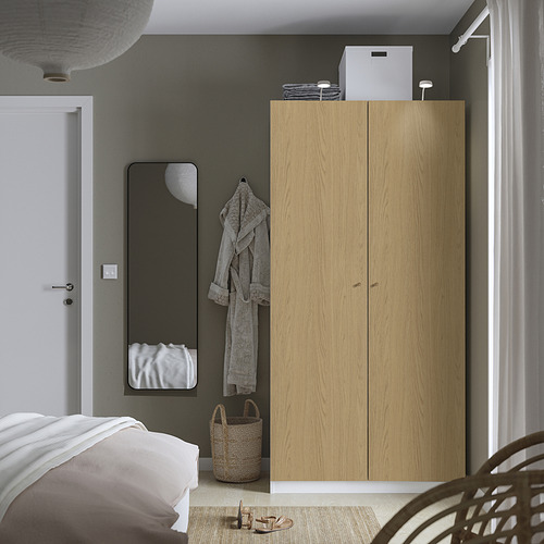 Dormitorio moderno con armario PAX, albornoz, cesta de suelo y lámpara colgante.