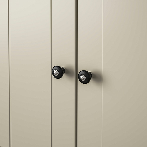 Primer plano de dos modernos pomos de armario en negro mate con tornillos de fijación cromados en una puerta de madera clara.