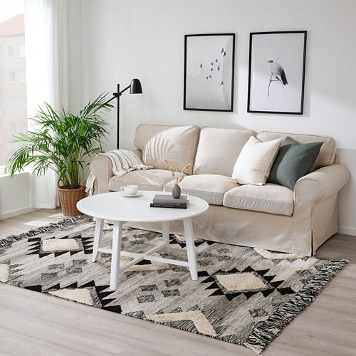 La alfombra beige de estilo marroquí TANNISBY encaja bien debajo del sofá neutro, agregando una textura suave a la sala de estar.