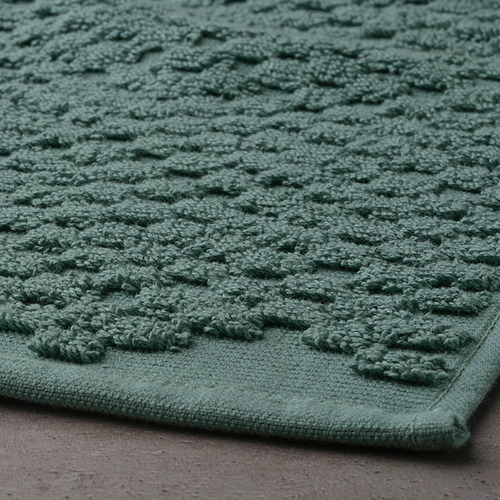 Alfombrilla de baño artesanal verde con superficie de punto texturizada y pelo grueso de algodón para mayor comodidad y alta absorción.