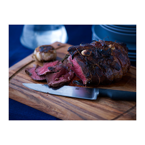 Un cuchillo en una tabla de cortar con carne a la parrilla.