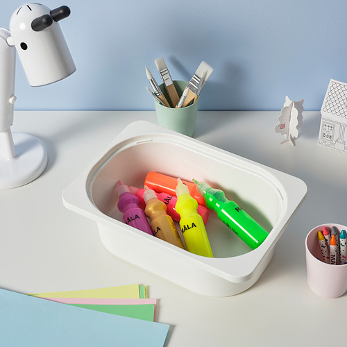 Rotuladores de colores en caja de almacenamiento TROFAST blanca junto a tazas de colores pastel con pinceles y papel de colores en el escritorio.