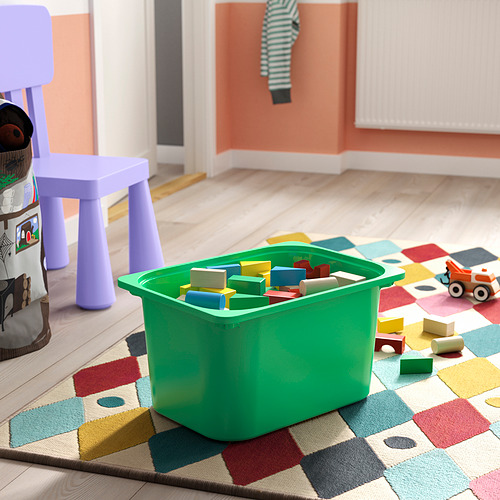 Gran contenedor de almacenamiento verde TROFAST lleno de bloques de colores, sobre una alfombra multicolor con un camión de juguete cerca.