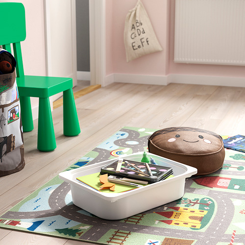 Sala de juegos con silla verde para niños, contenedor de almacenamiento de juguetes lleno de rompecabezas y formas, alfombra colorida y peluche.