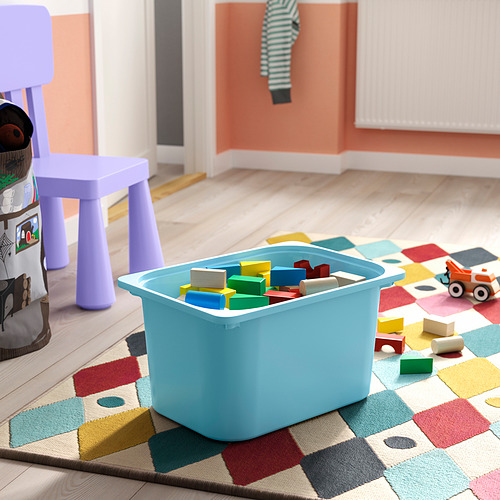 Un colorido contenedor de juguetes sobre una alfombra multicolor contiene bloques de construcción y un pequeño vehículo, adecuado para el juego y el almacenamiento de los niños.