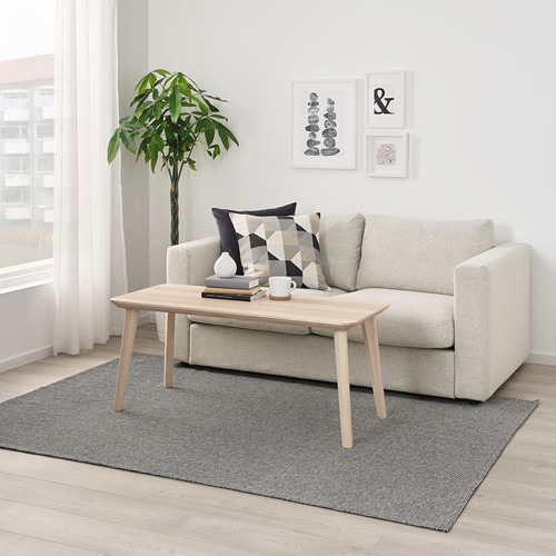 Sala de estar moderna con alfombra TIPHEDE gris claro, sofá blanco, mesa de centro de madera y planta. Arte en pared.