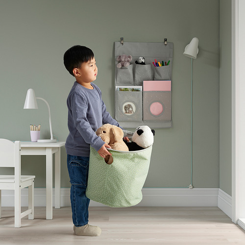 Un niño sosteniendo una bolsa de almacenamiento de lunares verdes con dos animales de peluche.