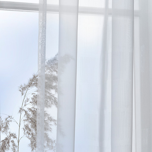 Las cortinas blancas transparentes con un patrón sutil difuminan suavemente la luz del día, creando privacidad mientras mantienen un aspecto sereno y minimalista.