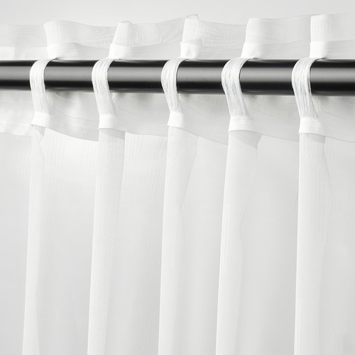 Las cortinas PALPLJUNGMAL cuelgan transparentes, blancas con una textura sutil, difundiendo la luz, ofreciendo privacidad al tiempo que permiten la conexión con el exterior.