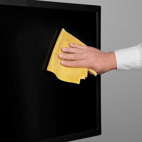 A mano con un paño amarillo limpiando la superficie negra, asegurando un resultado brillante y sin rayas.