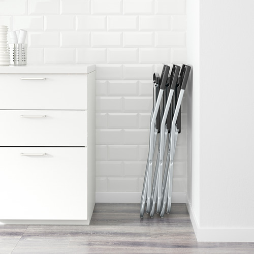 Sillas plegables apiladas contra la pared de azulejos blancos; Adecuado para ahorrar espacio.