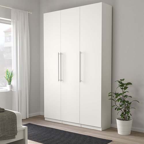 Gran armario blanco KALLRÖR junto a una planta y ventana, con tiradores de acero inoxidable.