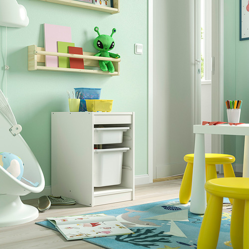 Habitación para niños con almacenamiento TROFAST en color blanco, con contenedores de colores. Es bajo, rectangular, con tres cajones. En las inmediaciones hay alfombras brillantes y taburetes amarillos.