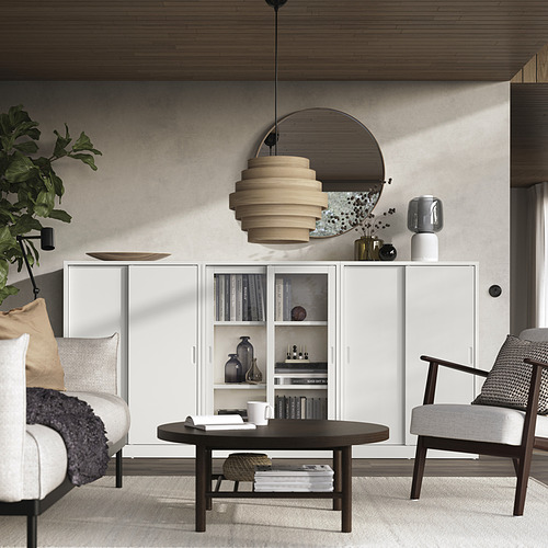 Moderno salón con mueble TONSTAD blanco, mesa redonda, sillas de madera, planta verde y lámpara colgante.