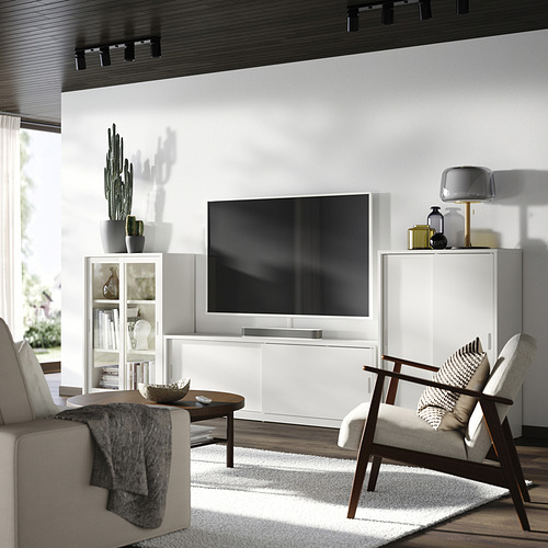 Sala de estar moderna con unidad de TV TONSTAD de color blanquecino, puertas corredizas, iluminación suave, detalles de madera y asientos acogedores.