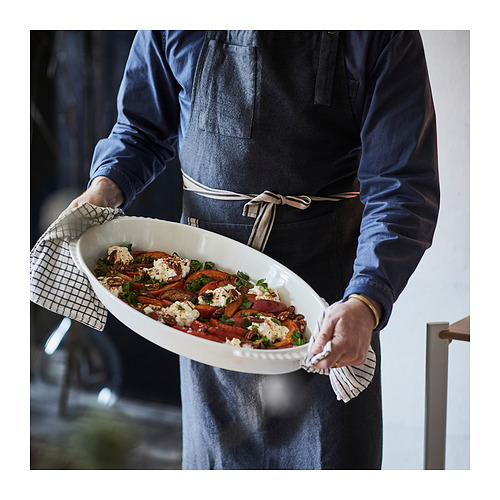 Persona sosteniendo un gran recipiente para horno con verduras asadas, listo para servir.