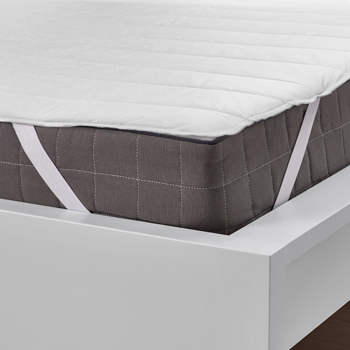 Protector de colchón blanco en la cama, correas elásticas para un ajuste seguro, protege el colchón de las manchas.