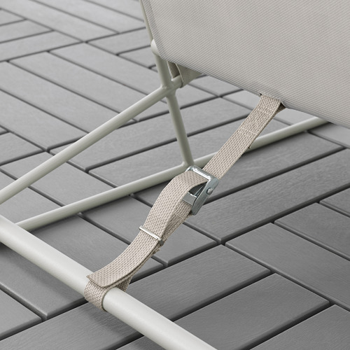 Primer plano de una correa ajustable en una silla de patio beige, probablemente parte de la serie HAVSTEN, diseñada para apretar o aflojar la tela de malla para mayor comodidad.