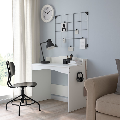 Pequeño escritorio blanco para niños, SMÅGÖRA, con silla de oficina negra. Incluye lámpara, auriculares, libros. Pared gris, reloj arriba.