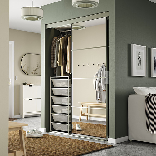 Dormitorio moderno con pared verde, almacenamiento JONAXEL incorporado, espejo, estantes, barra para colgar y luces colgantes.