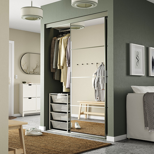 Almacenaje de acero JONAXEL con puerta de espejo en la habitación, organizando la ropa de forma ordenada.