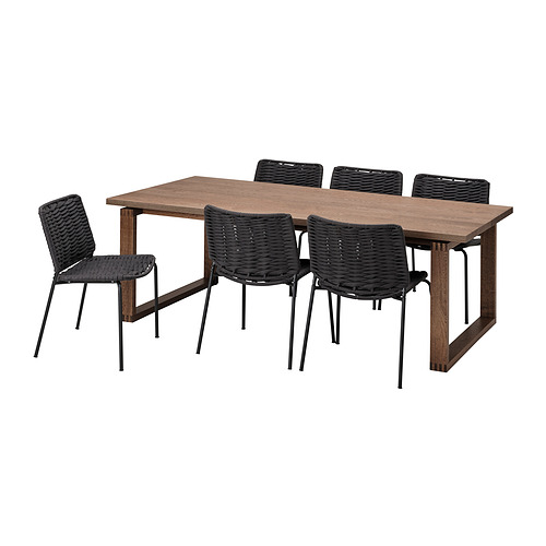 Un juego de comedor MÖRBYLÅNGA con mesa de madera y sillas negras. La mesa tiene tapa de color marrón claro, patas de metal; Las sillas tienen asientos/respaldos tejidos negros, marcos de metal.