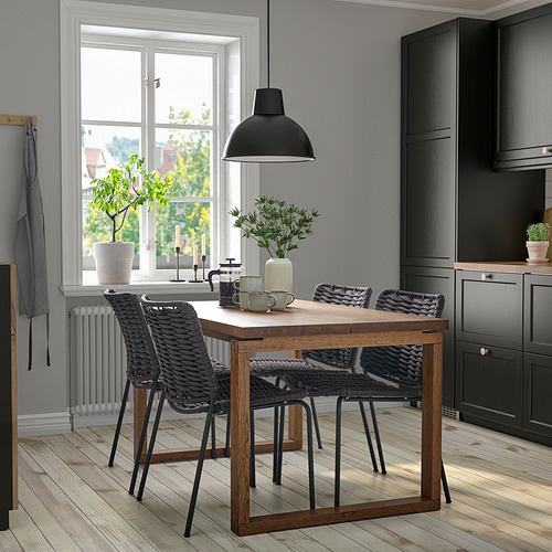 Rincón de cocina moderno con mesa MÖRBYLÅNGA de madera clara, sillas negras y lámpara colgante.
