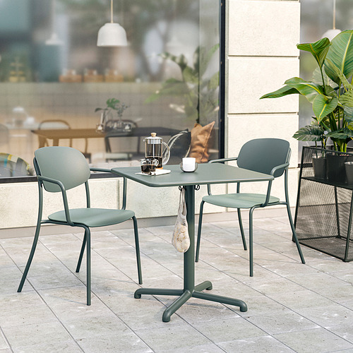 El pequeño juego de comedor al aire libre incluye una mesa de metal verde claro y sillas con cojines, adecuadas para espacios compactos.