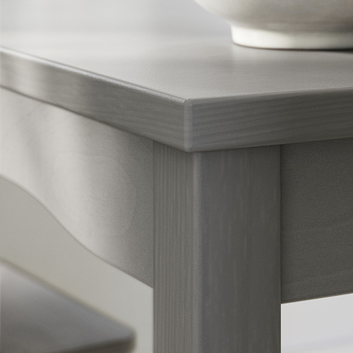 HAUGA: esquina de la mesa de madera gris, tapa lisa y borde angular.