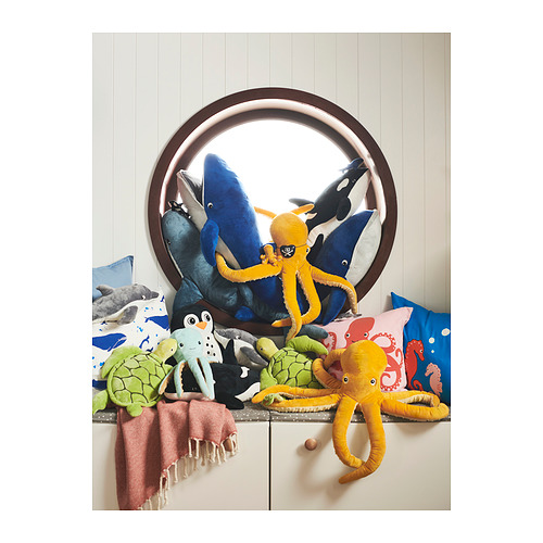 Una colección de coloridos juguetes de peluche de criaturas marinas, que incluyen tortugas, pulpos y delfines, exhibidos con cojines.