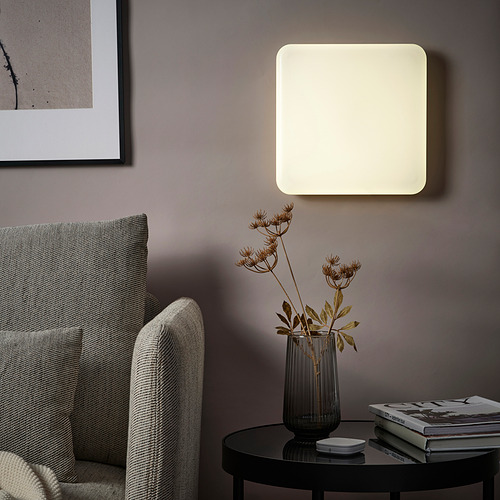 Sala de estar moderna con panel de luz JETSTRÖM, flores secas, silla, arte en pared morada.
