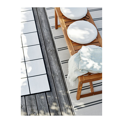Sillas de exterior de madera con cojines blancos y una manta azul claro.