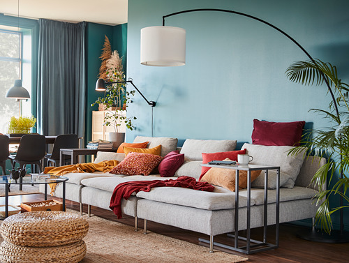 Acogedor salón con paredes azules, lámpara gris, lámpara colgante, sofá gris, plantas.