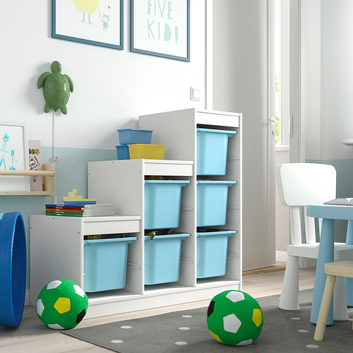 Habitación para niños con almacenamiento TROFAST, blanco, con contenedores de plástico azules. Un área lúdica con juguetes, libros y sillas.