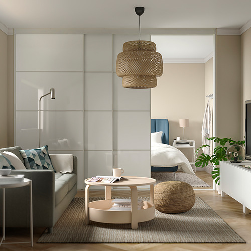 Sala de estar moderna con sofá gris, detalles en azul, mesa de centro de madera, taza de té, revista, taburete tejido, puerta de vidrio, colores brillantes y neutros.