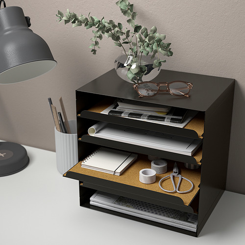 Organizador de escritorio negro con tres compartimentos, con capacidad para archivos, cuadernos y material de oficina, colocado junto a una lámpara y una planta.
