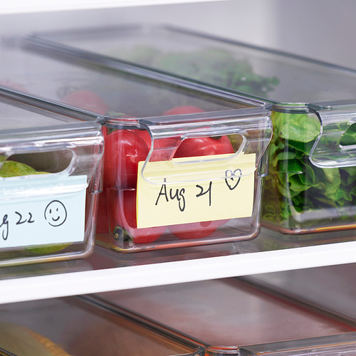 Los recipientes de plástico transparente del refrigerador con tapa, etiquetados con fechas, almacenan y organizan los alimentos de manera eficiente.