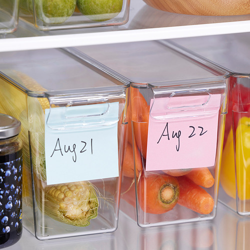 Los recipientes transparentes del refrigerador con tapas y fechas en las etiquetas almacenan productos frescos, organizados con fechas escritas.