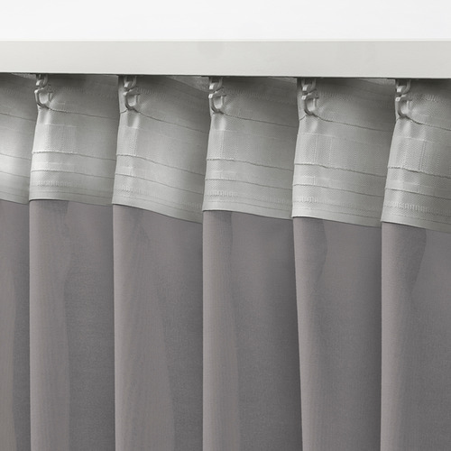 Cortinas grises transparentes con ganchos metálicos colgando, difundiendo la luz del día, ideales para tratamientos de ventanas en capas.